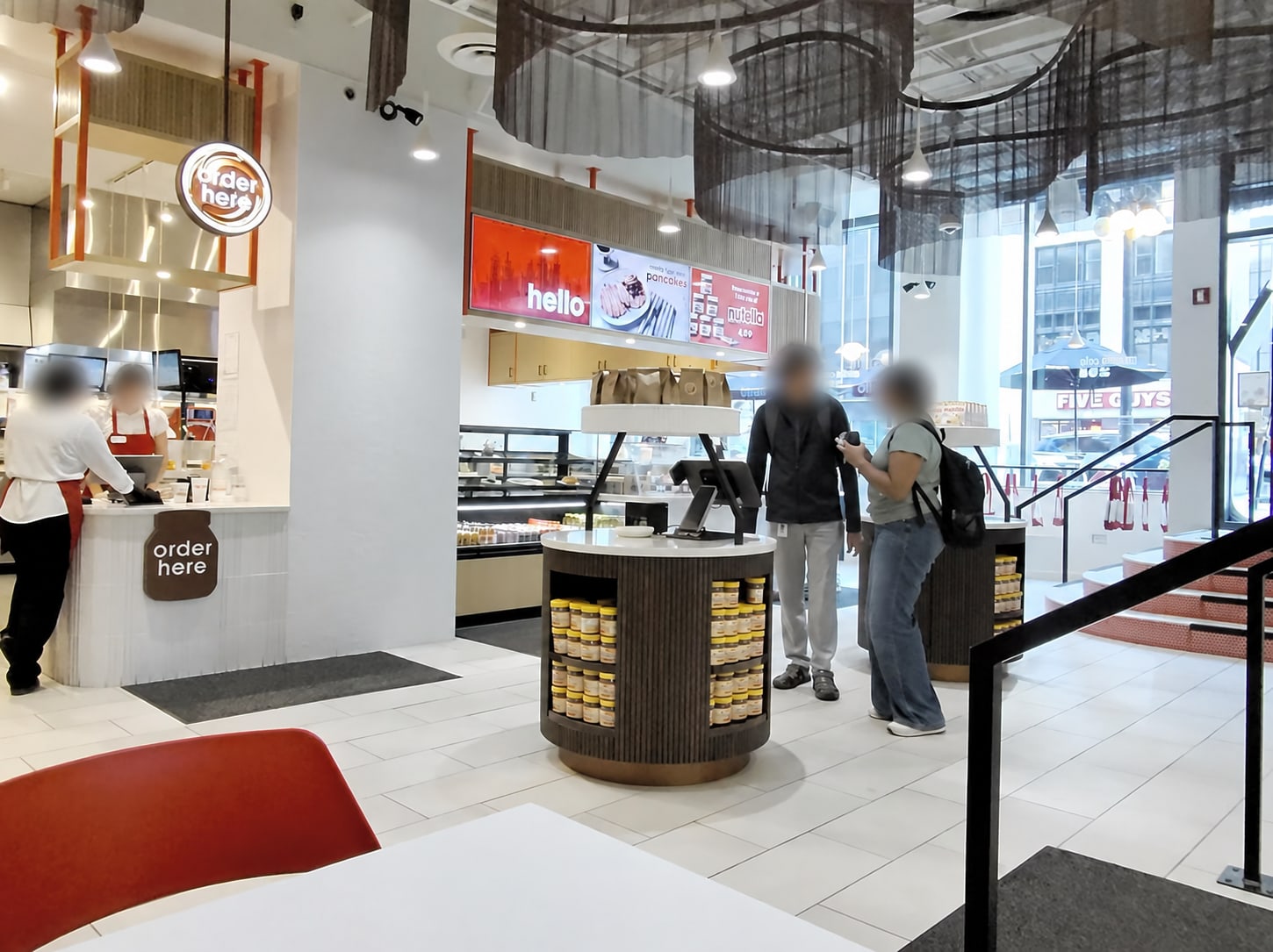 Intérieur du Nutella Café avec des marches et une rampe à droite ; visages des personnes floutés.