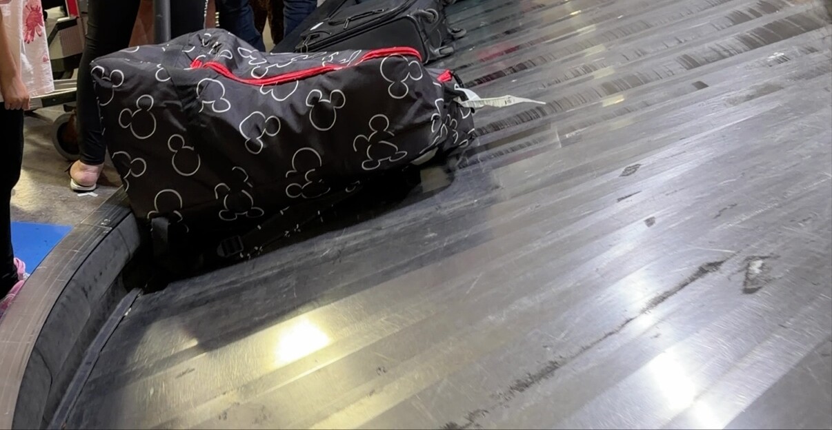 Siège auto protégé dans sa housse noire arrivant sur le tapis à bagages de Toronto